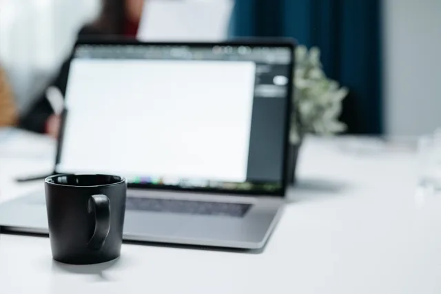 A black coffee mug on an office desk with a blurred laptop in the background. Choosing appointment setting agencies tools and providers without the guesswork