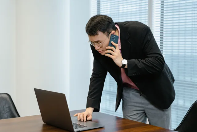 Asian businessman in the office multitasking with a laptop and smartphone call. Seven appointment setting agencies outlook shifts to watch
