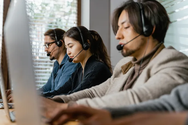 Three call center agents working diligently with headsets in an office setting, showcasing teamwork. What the UK rules on appointment setting agencies mean for outsourced sales teams