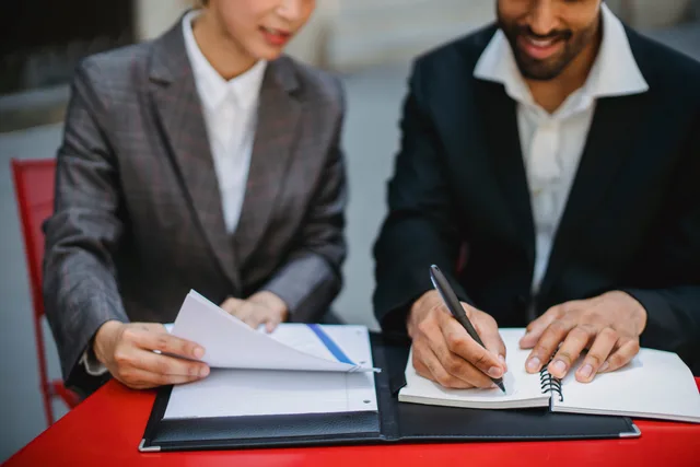 Two business professionals in suits reviewing documents and writing notes at a table. How to brief an appointment setting agency for accountancy firms