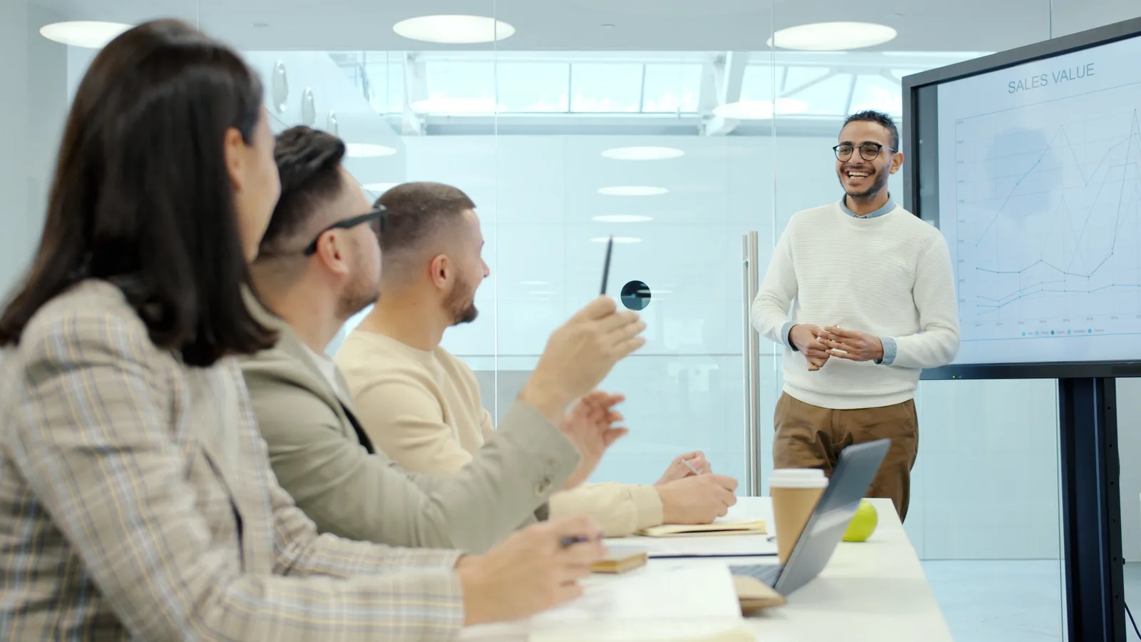 Team discussing sales graphs in a modern conference room.